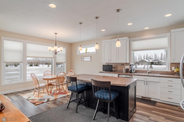 kitchen featuring white cabinetry, a kitchen island, sink, and pendant lighting