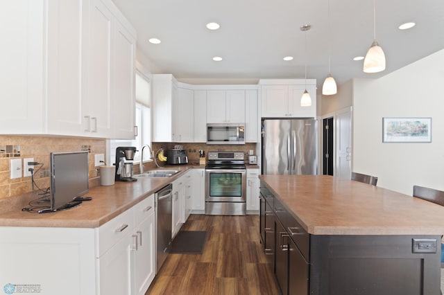 kitchen featuring sink, white cabinetry, a center island, pendant lighting, and stainless steel appliances