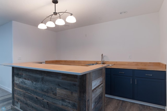 bar with blue cabinets, butcher block counters, sink, dark hardwood / wood-style floors, and pendant lighting