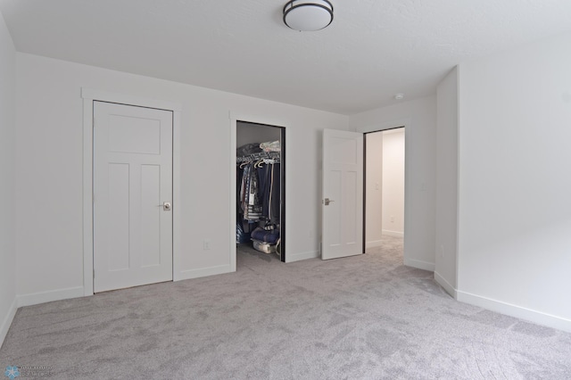 unfurnished bedroom featuring light colored carpet, a closet, and a walk in closet