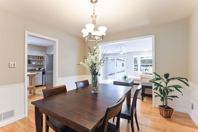 dining room with ceiling fan with notable chandelier and light hardwood / wood-style floors