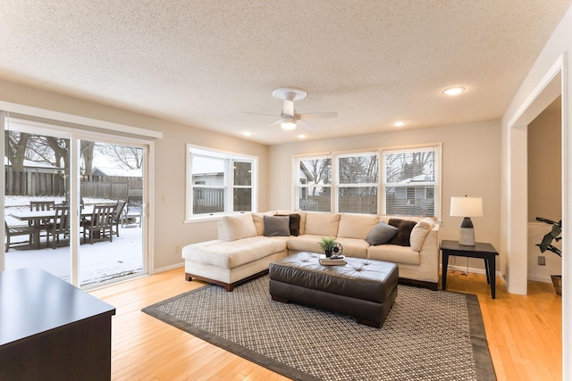 living room with ceiling fan, hardwood / wood-style flooring, and a textured ceiling