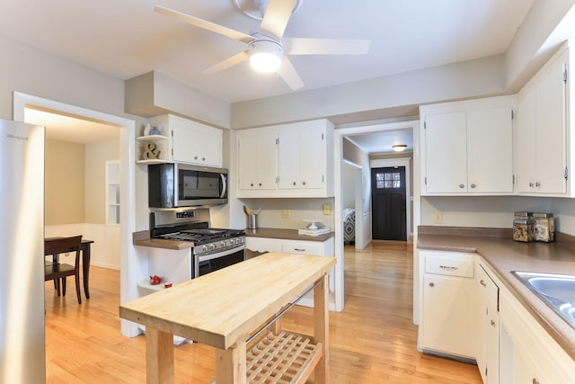 kitchen with stainless steel appliances, white cabinetry, ceiling fan, and light wood-type flooring