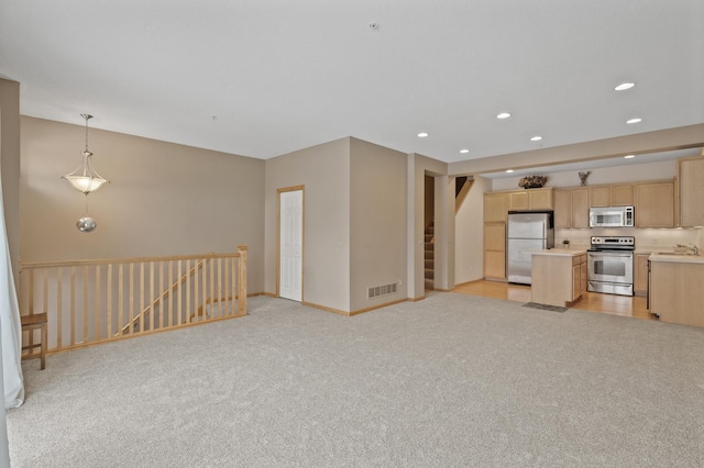 unfurnished living room featuring light colored carpet and sink