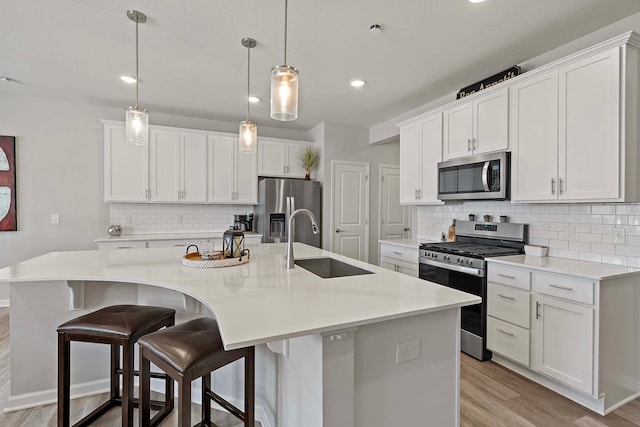 4884 Avery Ct, Eagan, MN 55123 - kitchen with appliances with stainless steel finishes, a sink, light wood finished floors, decorative backsplash, and a spacious island