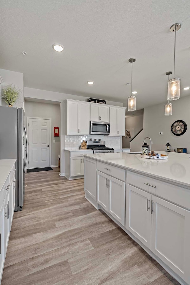 4884 Avery Ct, Eagan, MN 55123 - kitchen with stainless steel appliances, light countertops, white cabinets, decorative backsplash, and pendant lighting