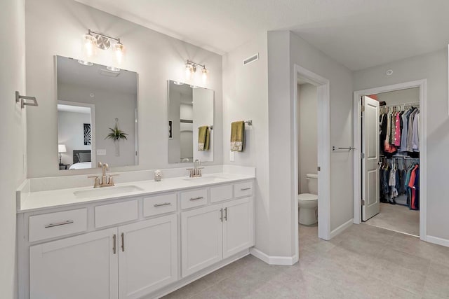 4884 Avery Ct, Eagan, MN 55123 - bathroom with double vanity, toilet, a spacious closet, tile patterned floors, and baseboards