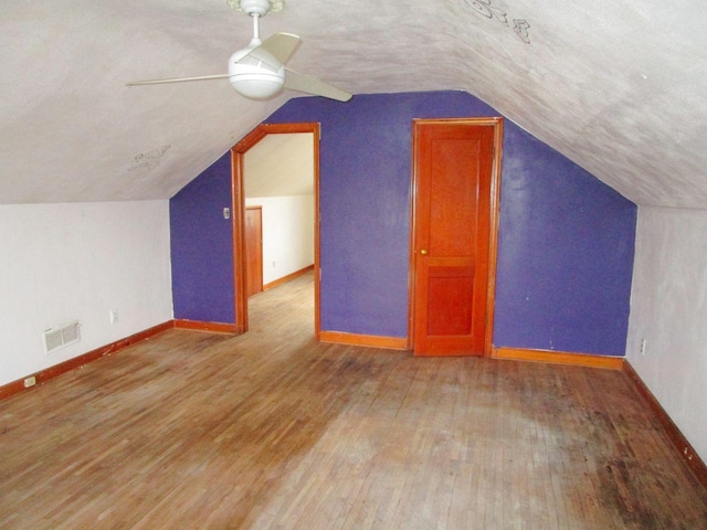 bonus room featuring hardwood / wood-style flooring, ceiling fan, lofted ceiling, and a textured ceiling