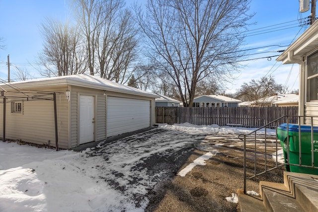 yard covered in snow featuring a garage, an outdoor structure, and fence