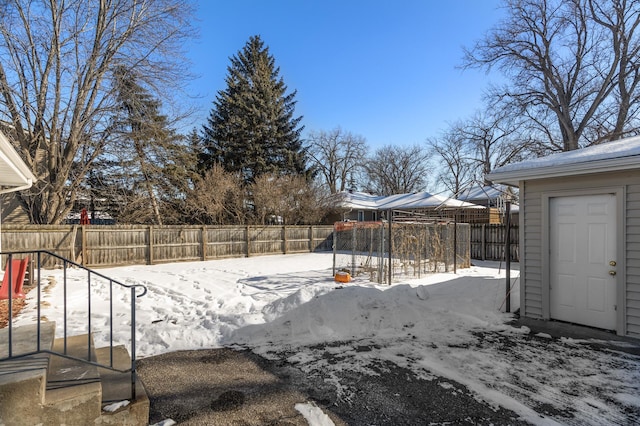 snowy yard featuring a playground and a fenced backyard