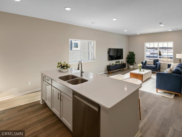 kitchen with open floor plan, stainless steel dishwasher, dark wood-style flooring, and a sink