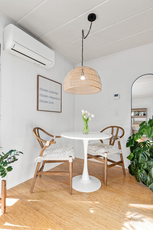 dining space featuring wood-type flooring and a wall mounted air conditioner