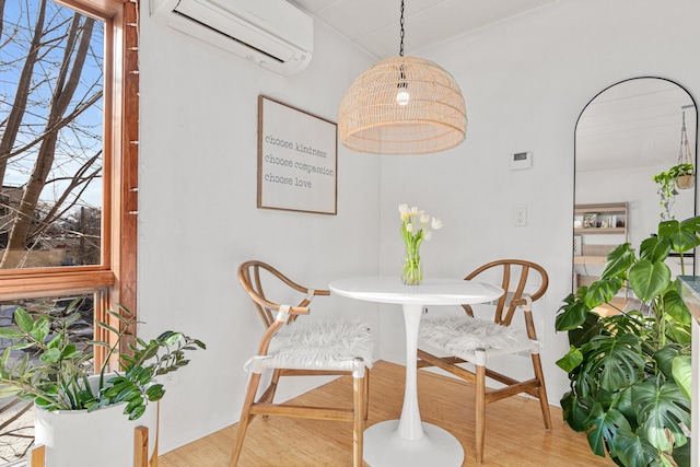 dining area featuring wood-type flooring and an AC wall unit