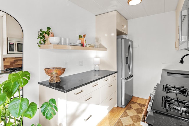 kitchen with stainless steel appliances, sink, white cabinets, and light wood-type flooring