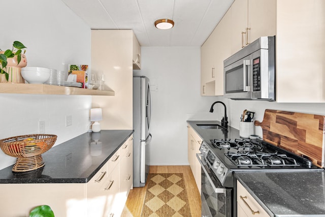 kitchen with appliances with stainless steel finishes, sink, and light wood-type flooring