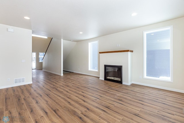 5476 Lori Ln W, West Fargo, ND 58078 - unfurnished living room featuring wood finished floors, a glass covered fireplace, recessed lighting, and baseboards