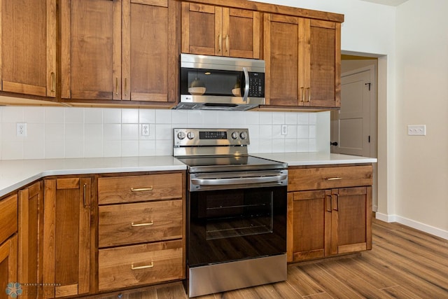 5476 Lori Ln W, West Fargo, ND 58078 - kitchen with stainless steel appliances, dark wood finished floors, brown cabinetry, and baseboards