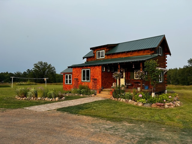 view of front of property featuring a porch, metal roof, and a front lawn