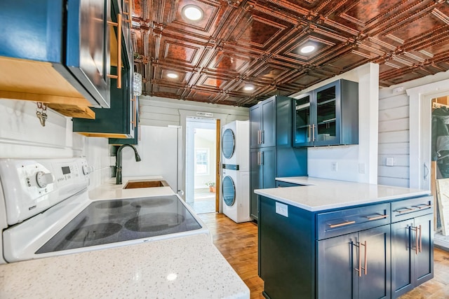 kitchen with a sink, an ornate ceiling, white electric range oven, light countertops, and stacked washer / dryer