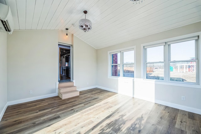 spare room with a wall mounted air conditioner, baseboards, lofted ceiling, and wood finished floors