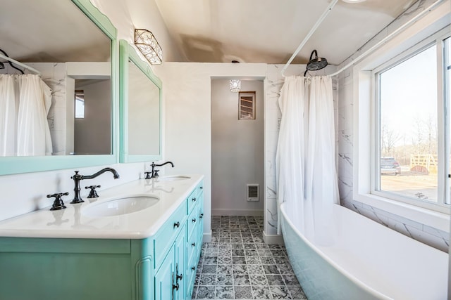 bathroom with double vanity, a healthy amount of sunlight, and a sink