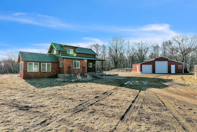 view of front of property featuring an outdoor structure, metal roof, a garage, and dirt driveway