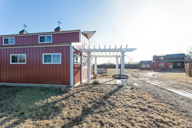 view of home's exterior with board and batten siding and a pergola