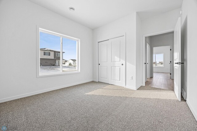 unfurnished bedroom with light colored carpet and a closet