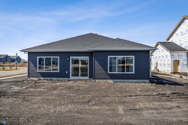 rear view of house featuring roof with shingles