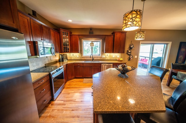 2441 Rosewood Ln SW, Rochester, MN 55902 - kitchen featuring appliances with stainless steel finishes, a kitchen bar, a sink, light wood-type flooring, and glass insert cabinets