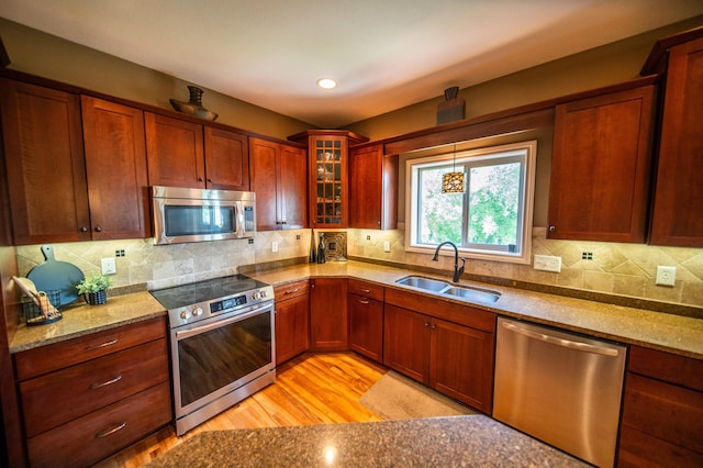 2441 Rosewood Ln SW, Rochester, MN 55902 - kitchen with appliances with stainless steel finishes, a sink, light stone counters, glass insert cabinets, and light wood finished floors