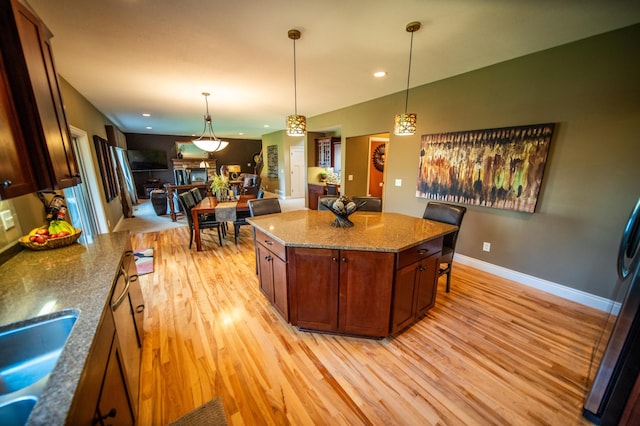 2441 Rosewood Ln SW, Rochester, MN 55902 - kitchen featuring light wood finished floors, a sink, baseboards, decorative light fixtures, and a center island
