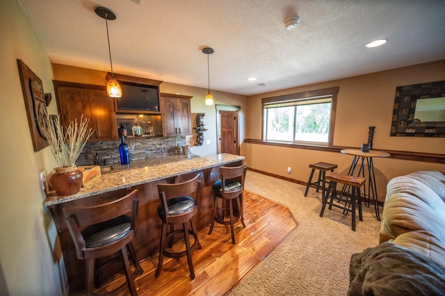 2441 Rosewood Ln SW, Rochester, MN 55902 - indoor dry bar featuring tasteful backsplash, baseboards, pendant lighting, a textured ceiling, and light carpet