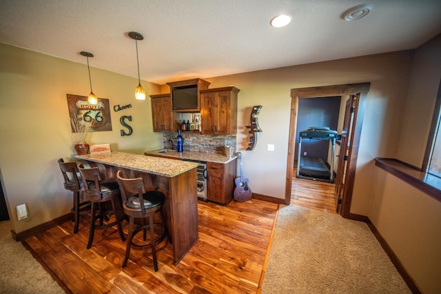 2441 Rosewood Ln SW, Rochester, MN 55902 - kitchen featuring a breakfast bar, a peninsula, baseboards, tasteful backsplash, and light stone counters
