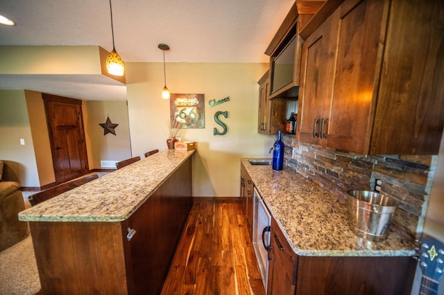 2441 Rosewood Ln SW, Rochester, MN 55902 - kitchen featuring a peninsula, tasteful backsplash, light stone countertops, dark wood-style flooring, and a textured ceiling