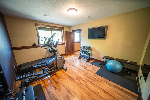 2441 Rosewood Ln SW, Rochester, MN 55902 - exercise area featuring light wood-type flooring, a textured ceiling, and baseboards