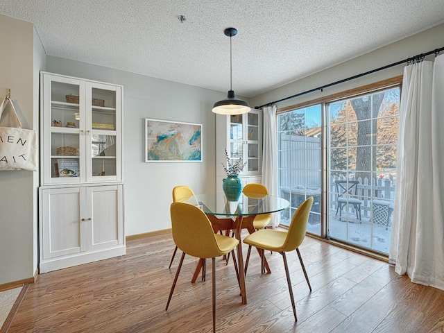 dining space featuring a textured ceiling, wood finished floors, and baseboards