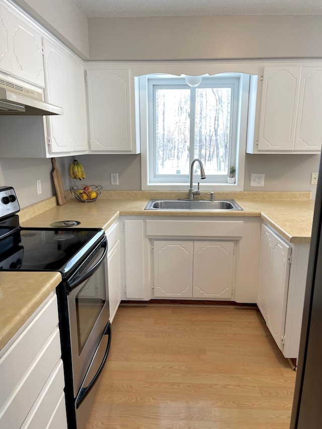 kitchen with sink, light wood-type flooring, white cabinets, and appliances with stainless steel finishes