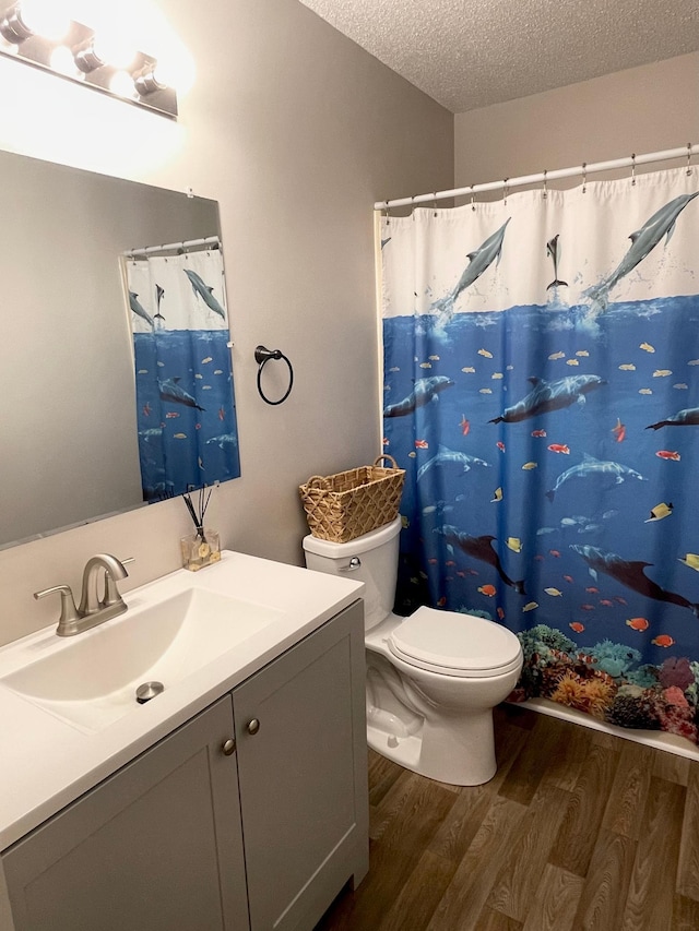 bathroom with wood-type flooring, toilet, a textured ceiling, and vanity