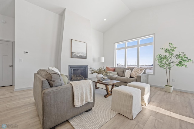 living room with high vaulted ceiling and light hardwood / wood-style flooring