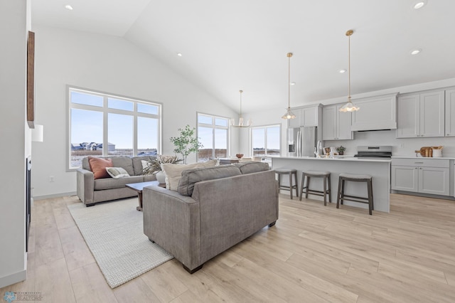 living room with sink, high vaulted ceiling, light hardwood / wood-style flooring, and a notable chandelier