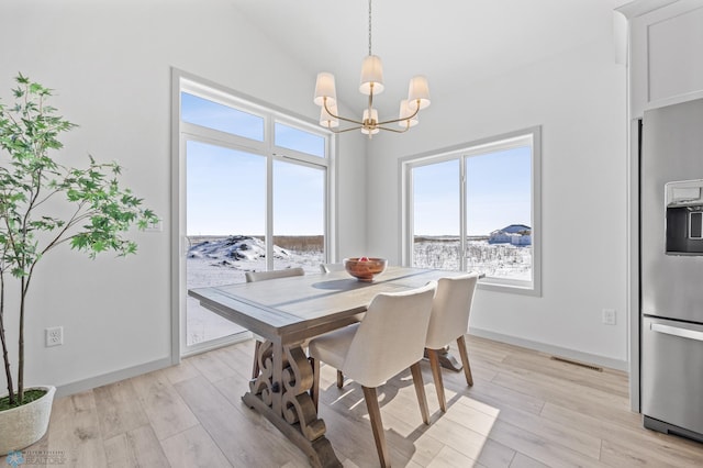 dining room featuring lofted ceiling, light hardwood / wood-style floors, and a chandelier