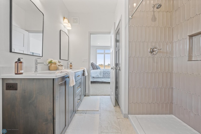 bathroom with a tile shower, vanity, and tile patterned floors