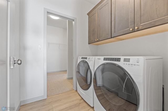 laundry room featuring cabinets, light hardwood / wood-style floors, and washing machine and clothes dryer