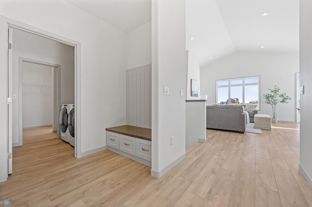 corridor featuring washer and dryer, high vaulted ceiling, and light hardwood / wood-style flooring