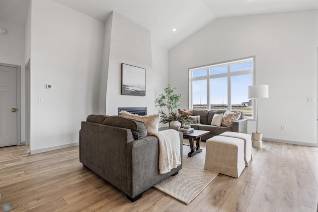 living room with high vaulted ceiling, baseboards, light wood finished floors, and a fireplace