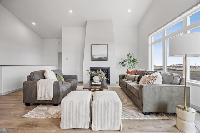 living room with recessed lighting, high vaulted ceiling, a fireplace, and light wood-type flooring