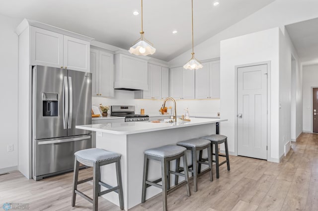kitchen featuring a kitchen bar, appliances with stainless steel finishes, light wood-type flooring, light countertops, and lofted ceiling
