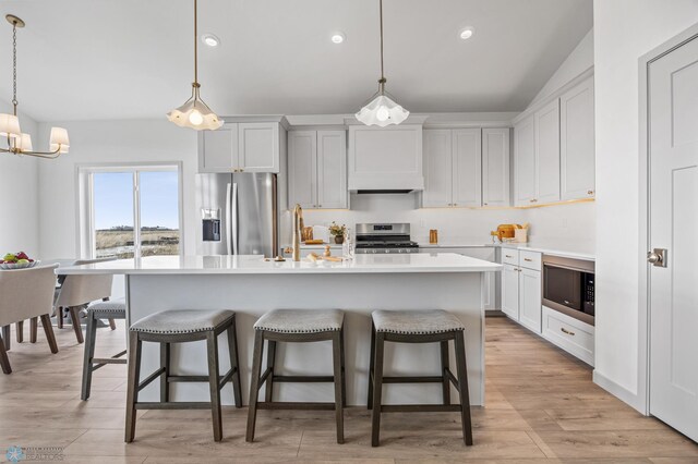 kitchen featuring a sink, a kitchen island with sink, a breakfast bar, and stainless steel appliances