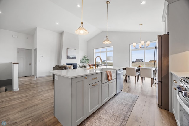 kitchen featuring light wood-type flooring, light countertops, gray cabinets, a sink, and appliances with stainless steel finishes